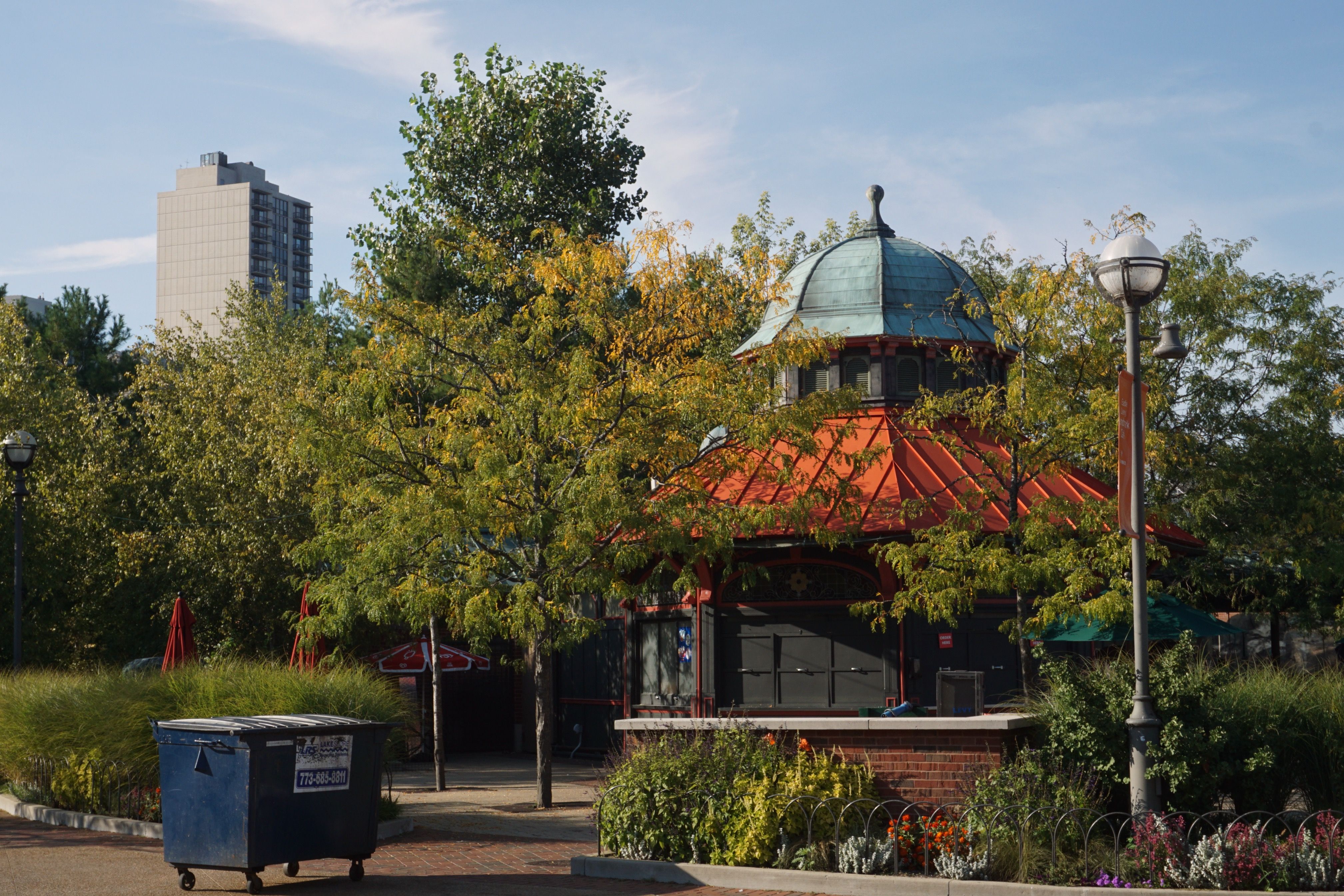 Serene park setting with a pavilion and urban backdrop under a clear sky.