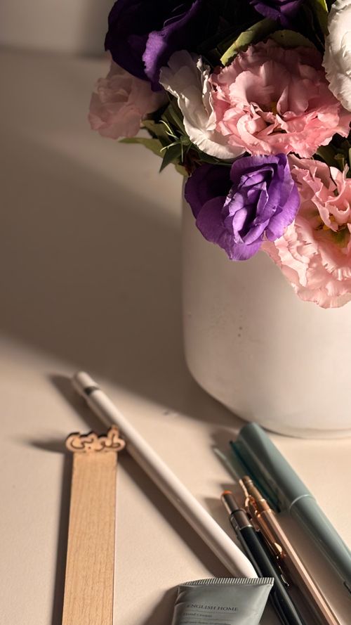 Free A beautiful floral bouquet in a vase accompanied by pens and stationery on a desk, bathed in warm light. Stock Photo