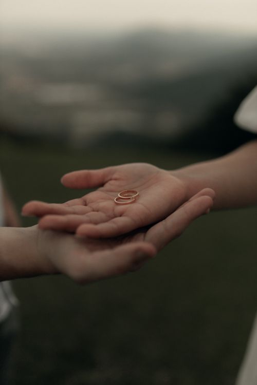 Free A close-up of hands exchanging wedding rings outdoors, symbolizing love and commitment. Stock Photo
