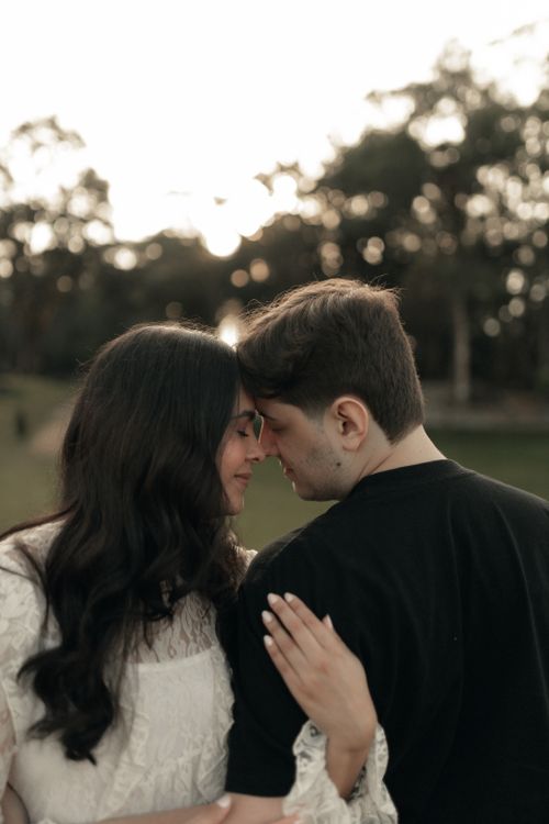 Free A couple enjoying a tender moment in an outdoor setting during sunset. Stock Photo