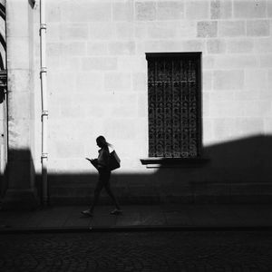 Woman walking beside a sunlit wall — photo by Alexis B on Pexels