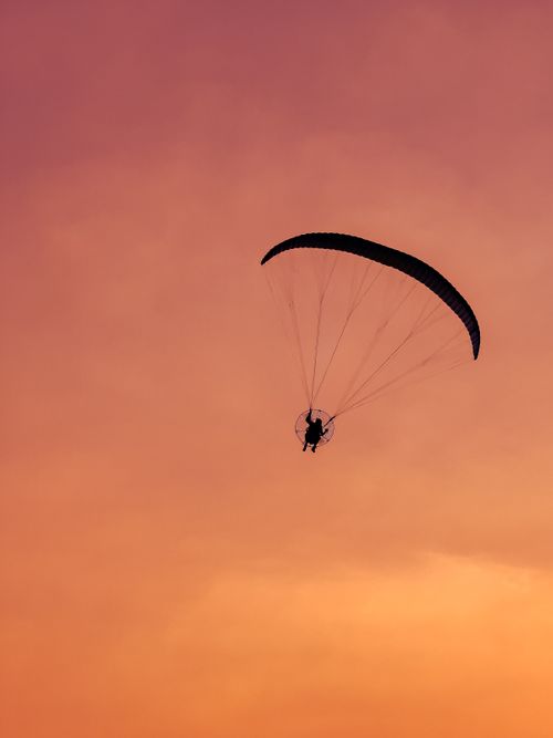 Free A paraglider silhouetted against a vibrant sunset sky in Dubai, UAE, capturing a sense of adventure. Stock Photo