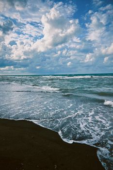 Captivating ocean scene with waves crashing on a sandy beach under a cloudy sky.