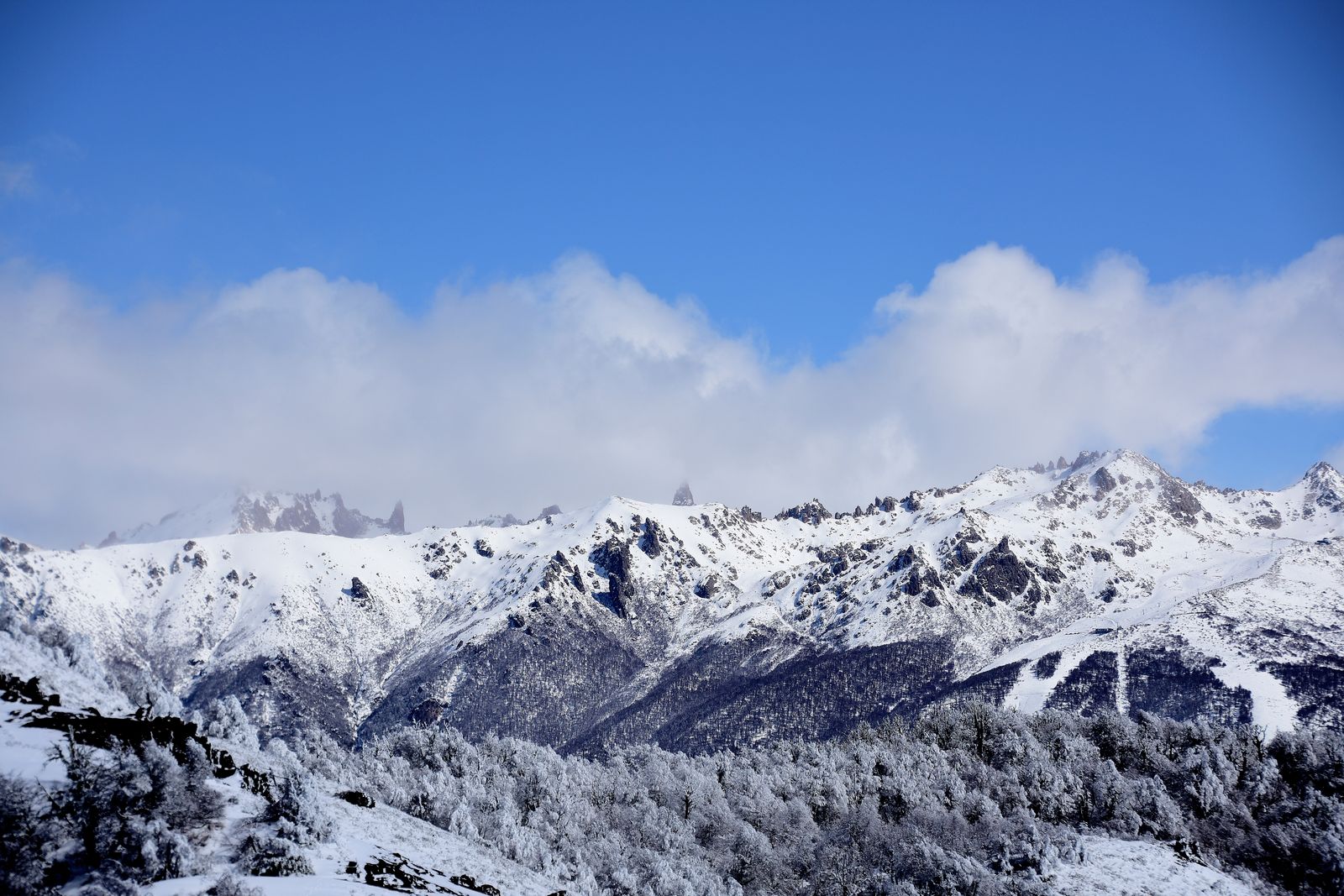 Stunning snowy mountains under a bright blue sky in Bariloche, Argentina.
