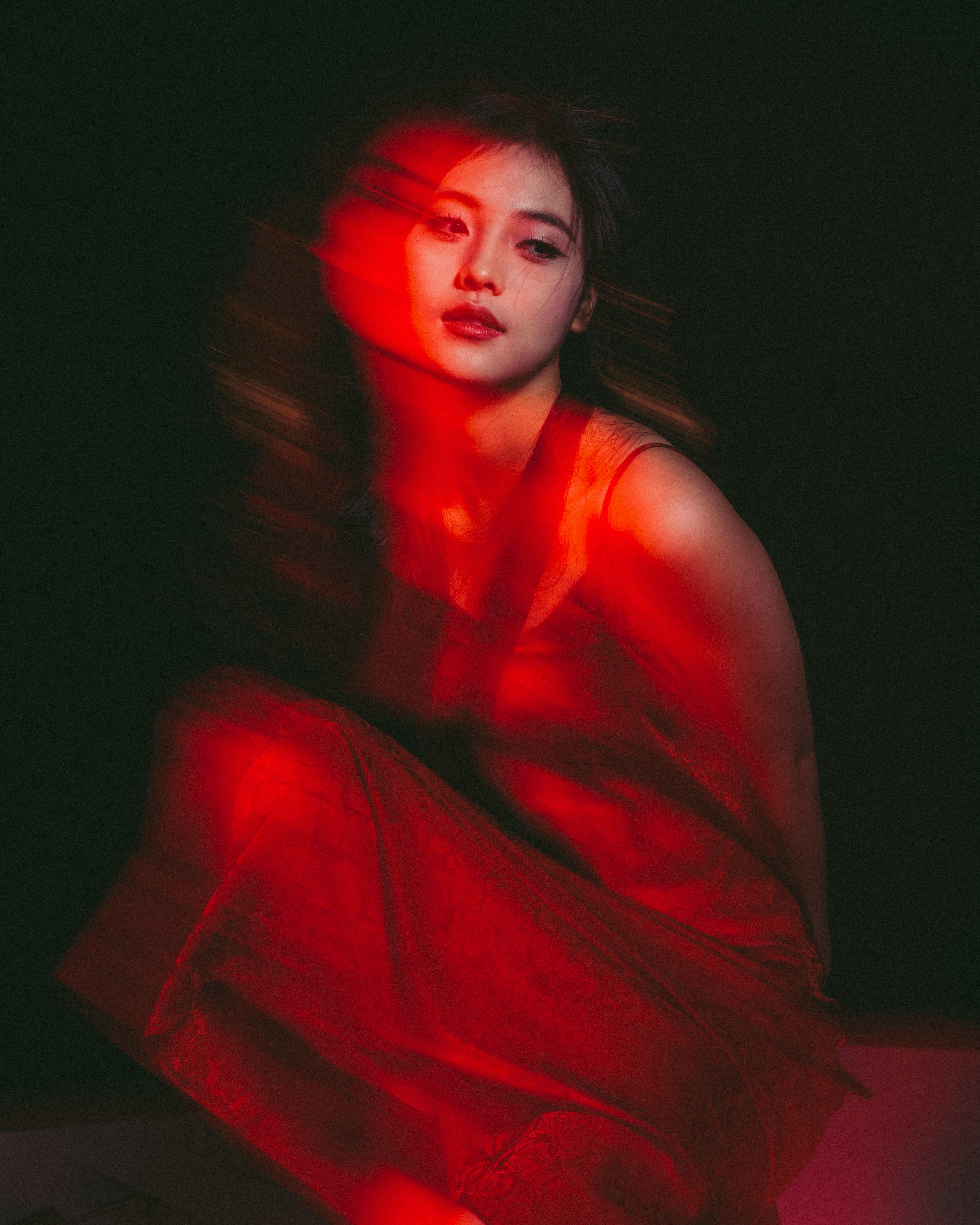 Creative portrait of a woman using long exposure and red lighting effects.