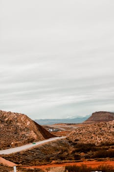Majestic view of Utah's desert landscape with red rock hills and cloudy sky.