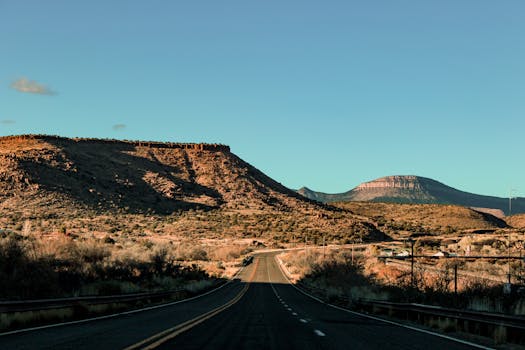Drive through Arizona's breathtaking desert landscape with stunning red rock formations under a clear blue sky.