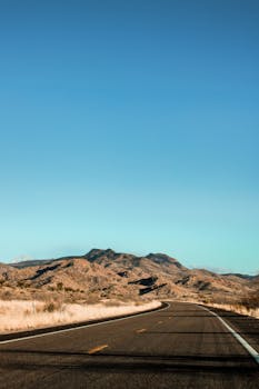 A picturesque view of a highway traversing the arid Arizona desert with mountains in the distance.