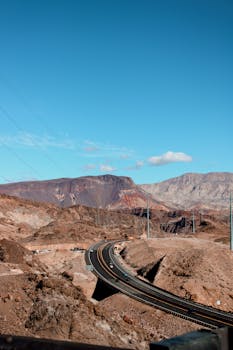 Scenic view of a desert highway winding through Arizona's mountainous terrain under a clear blue sky.