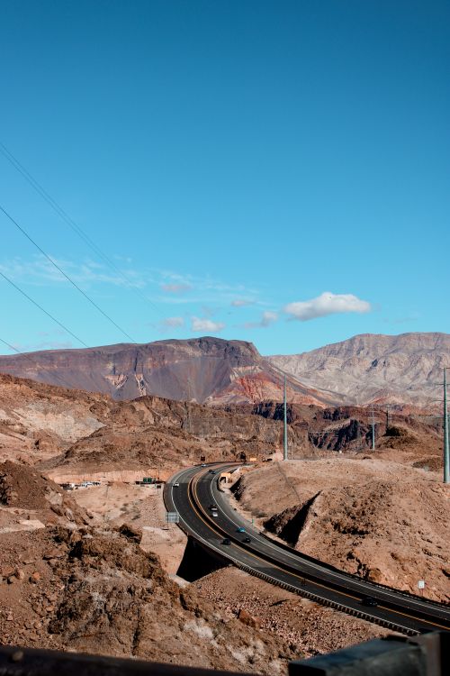 Free Scenic view of a desert highway winding through Arizona's mountainous terrain under a clear blue sky. Stock Photo