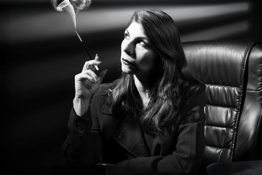 Sophisticated black and white portrait of a woman smoking, evoking film noir style.