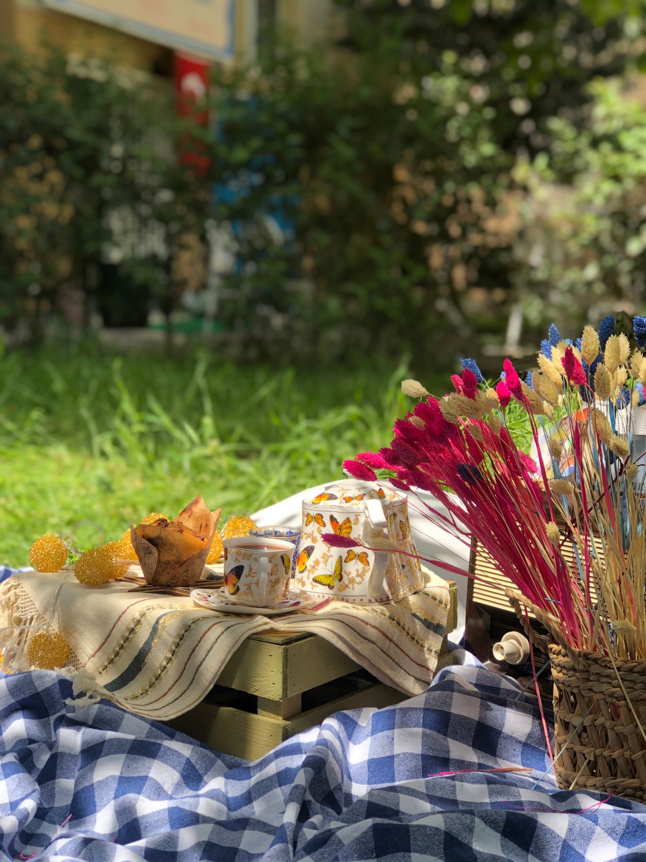 gingham-checkered-picnic-blankets A picnic setup with a checkered blanket in a sunny garden