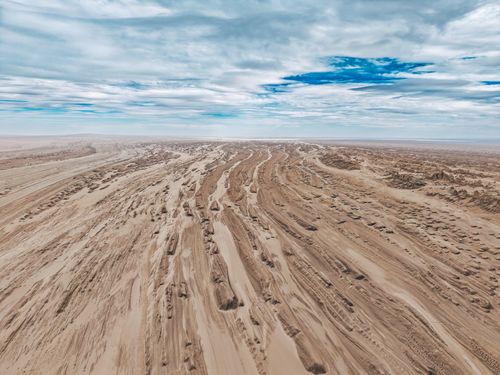 Free Expansive aerial view of a desert landscape under a dramatic cloudy sky, showcasing natural formations. Stock Photo