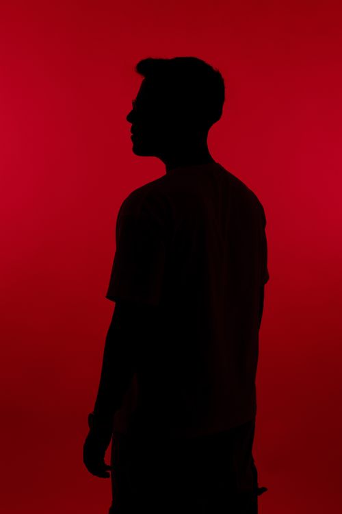 Free Artistic silhouette of a person standing against a vivid red backdrop, creating a dramatic and mysterious atmosphere. Stock Photo