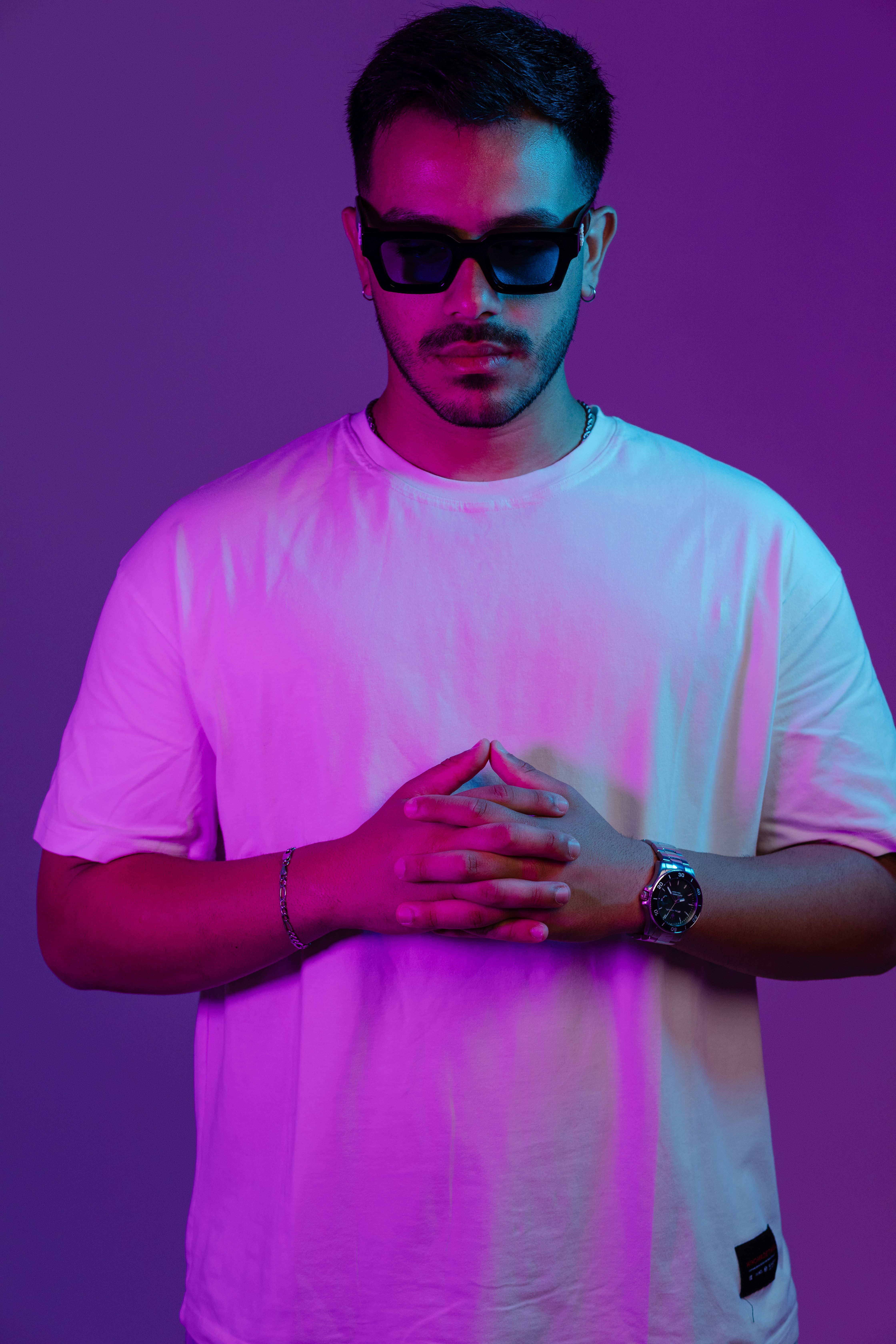 Stylish portrait of a man in sunglasses with vibrant pink and blue lighting.