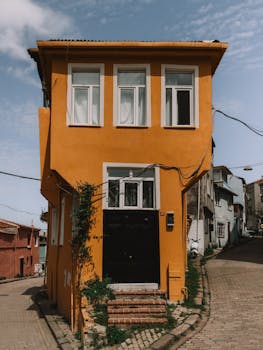 Colorful architecture of an orange house on a sunny day in Istanbul, Türkiye, capturing street life.
