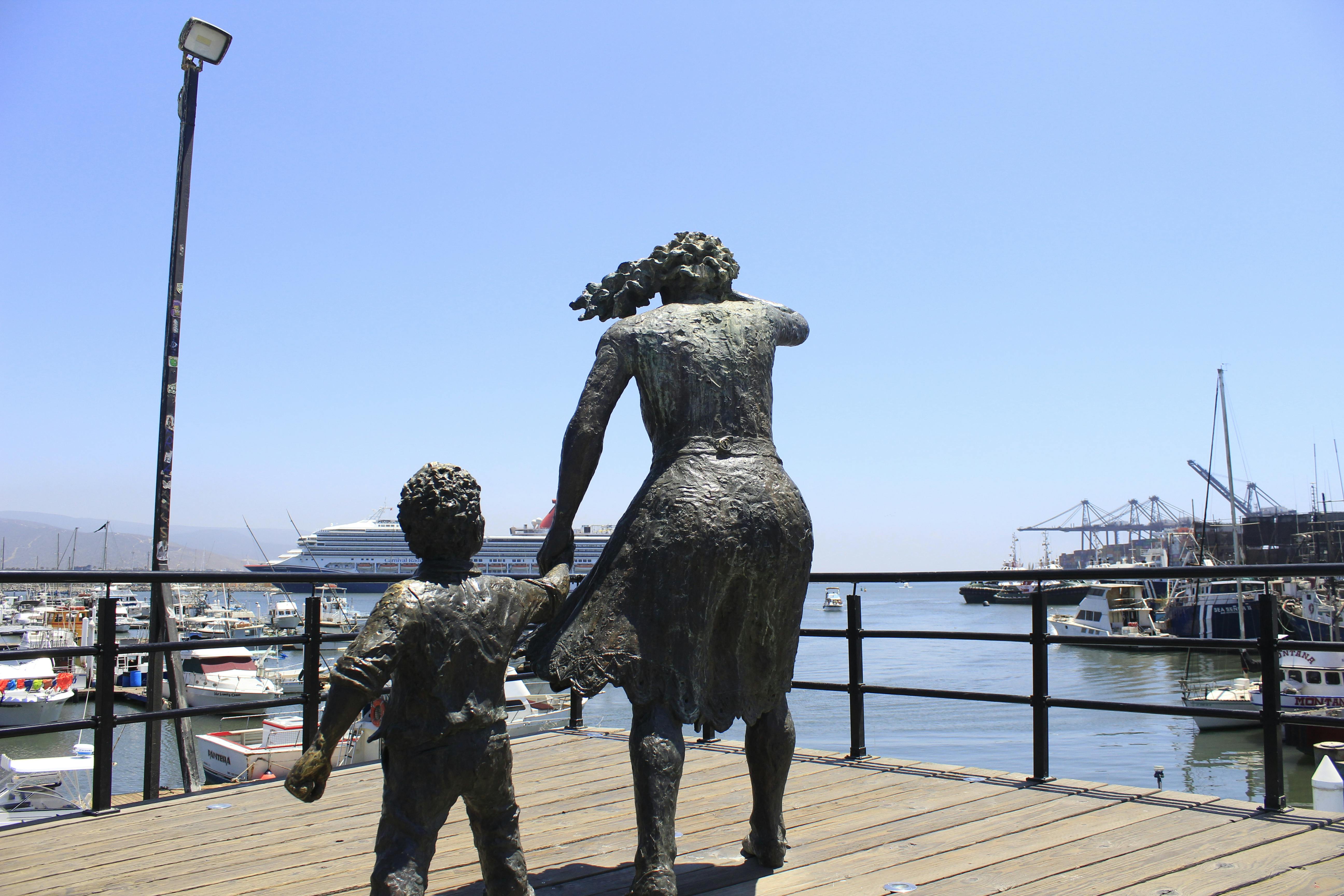 bronze statues of a woman and child overlooking a vibrant harbor with boats and a cruise ship. - Valparaíso