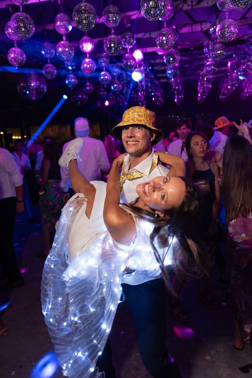 Free Couple dancing joyfully under disco balls at a lively wedding party. Stock Photo