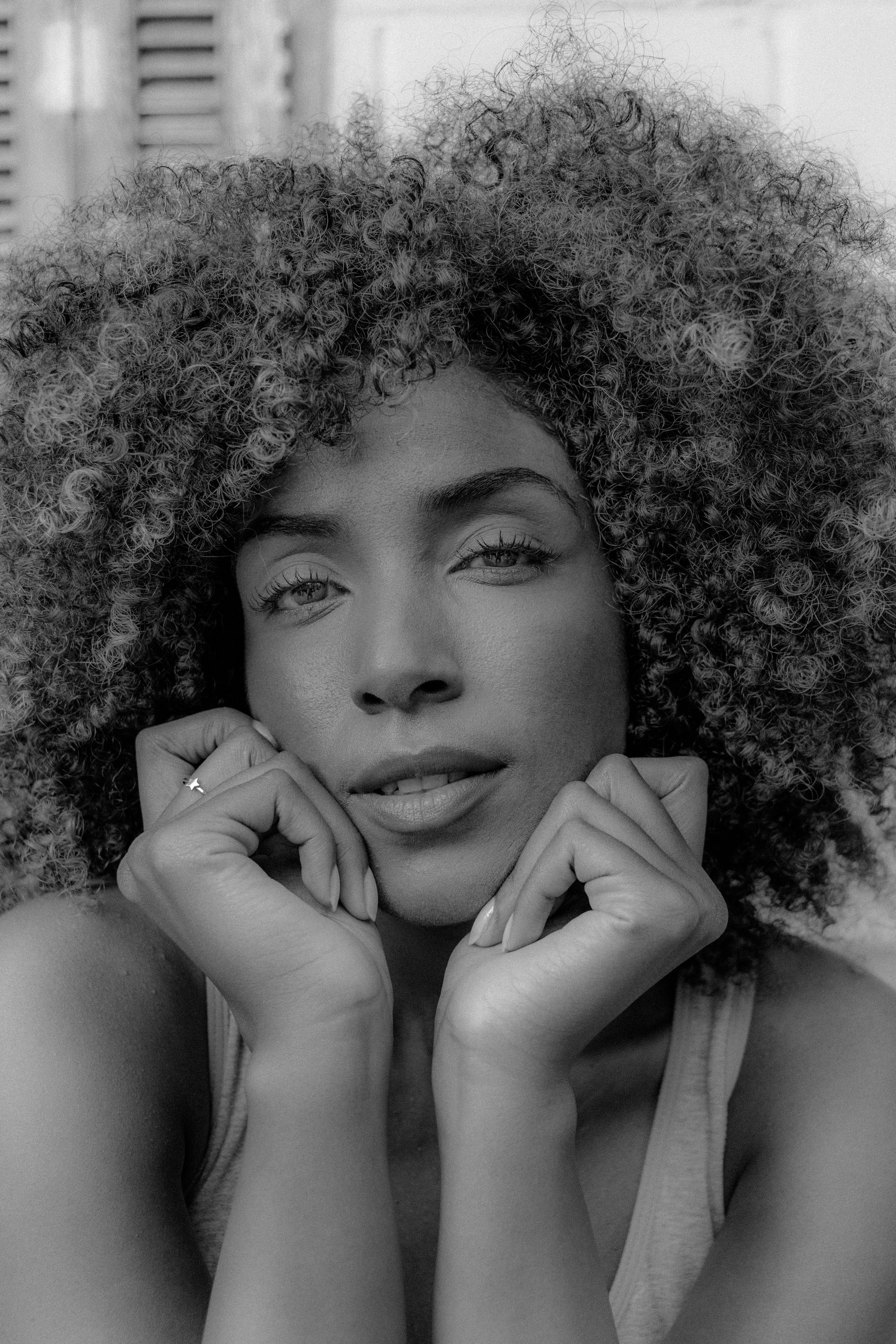 Black and white portrait of a woman with curly hair, showing natural beauty.