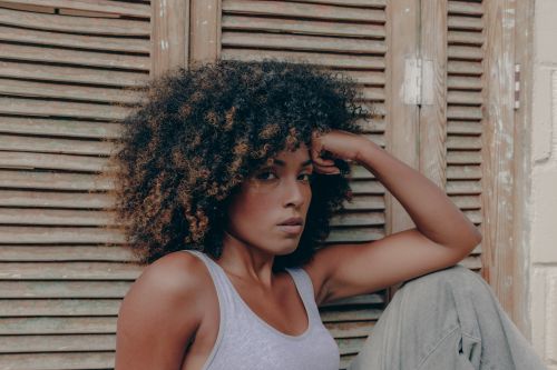 Free Side profile portrait of a woman with curly hair sitting indoors, showcasing natural beauty and relaxed pose. Stock Photo