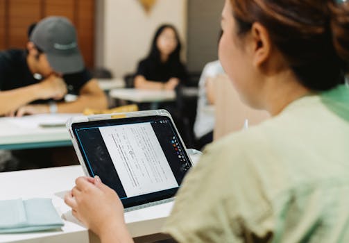 Students in a Japanese classroom using a tablet for digital learning, fostering modern education.