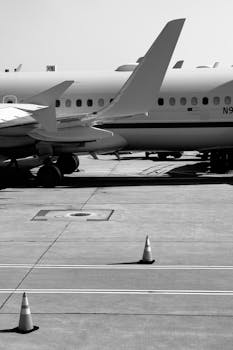 Black and white view of airplanes parked on the tarmac, highlighting aviation engineering.