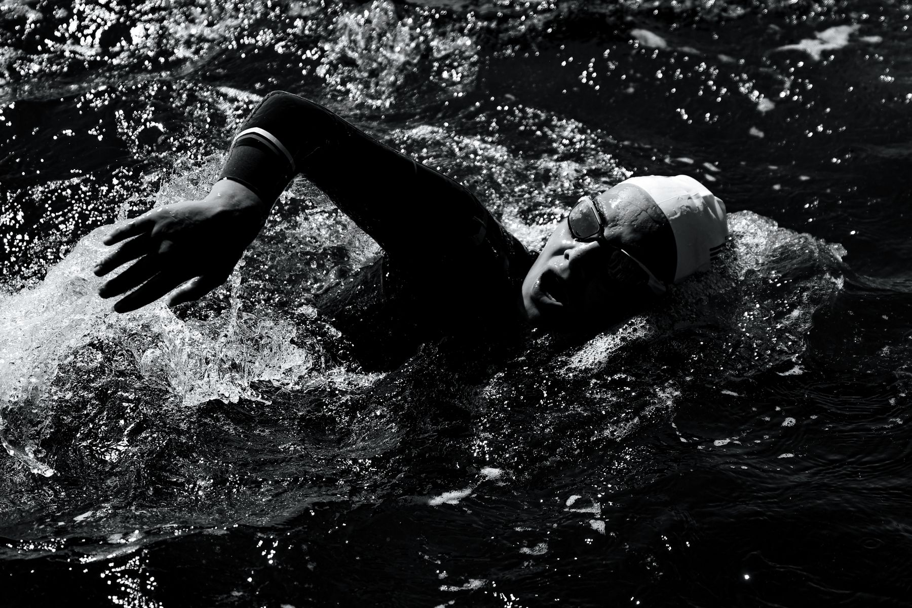 Dynamic black-and-white triathlon swim start with athletes churning the water