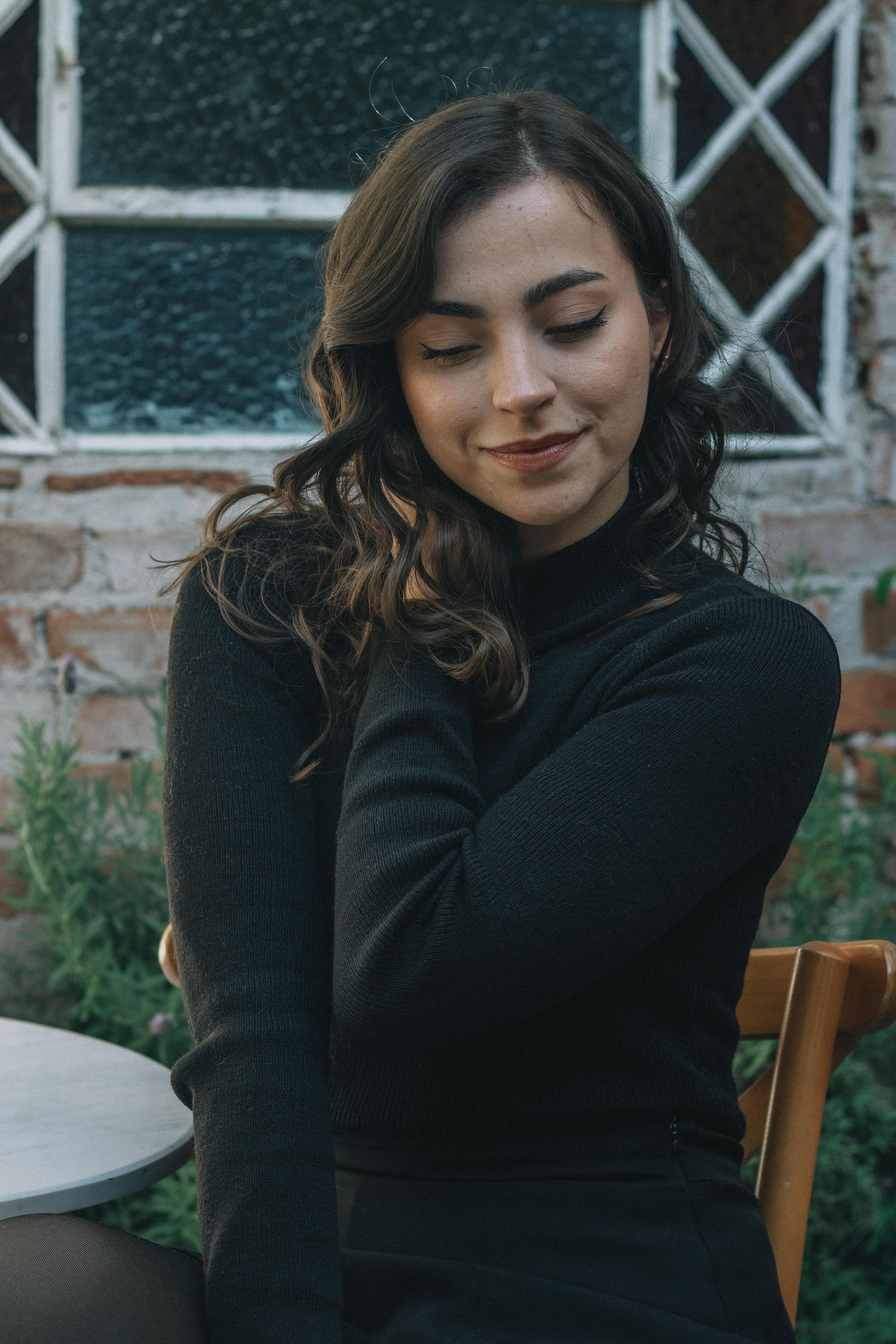 Gratis Sjarmerende kvinne i svart polotrøye poserer grasiøst utendørs, og utstråler eleganse og stil. Arkivbilde