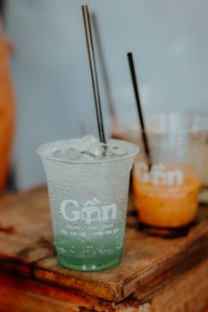 Close-up of colorful iced drinks on a rustic wooden table, featuring green and orange hues.