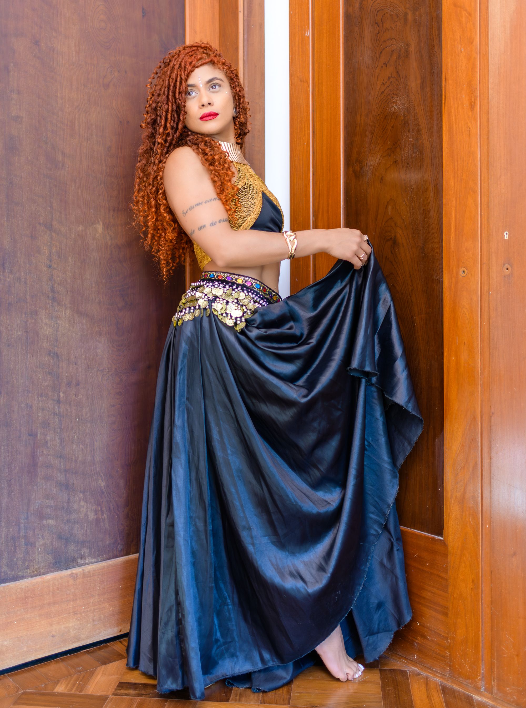 Beautiful woman in a flowing dress posing indoors, expressing grace and elegance.