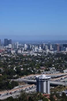 Aerial perspective of Los Angeles showcasing urban sprawl, freeways, and distant skyscrapers on a clear day.