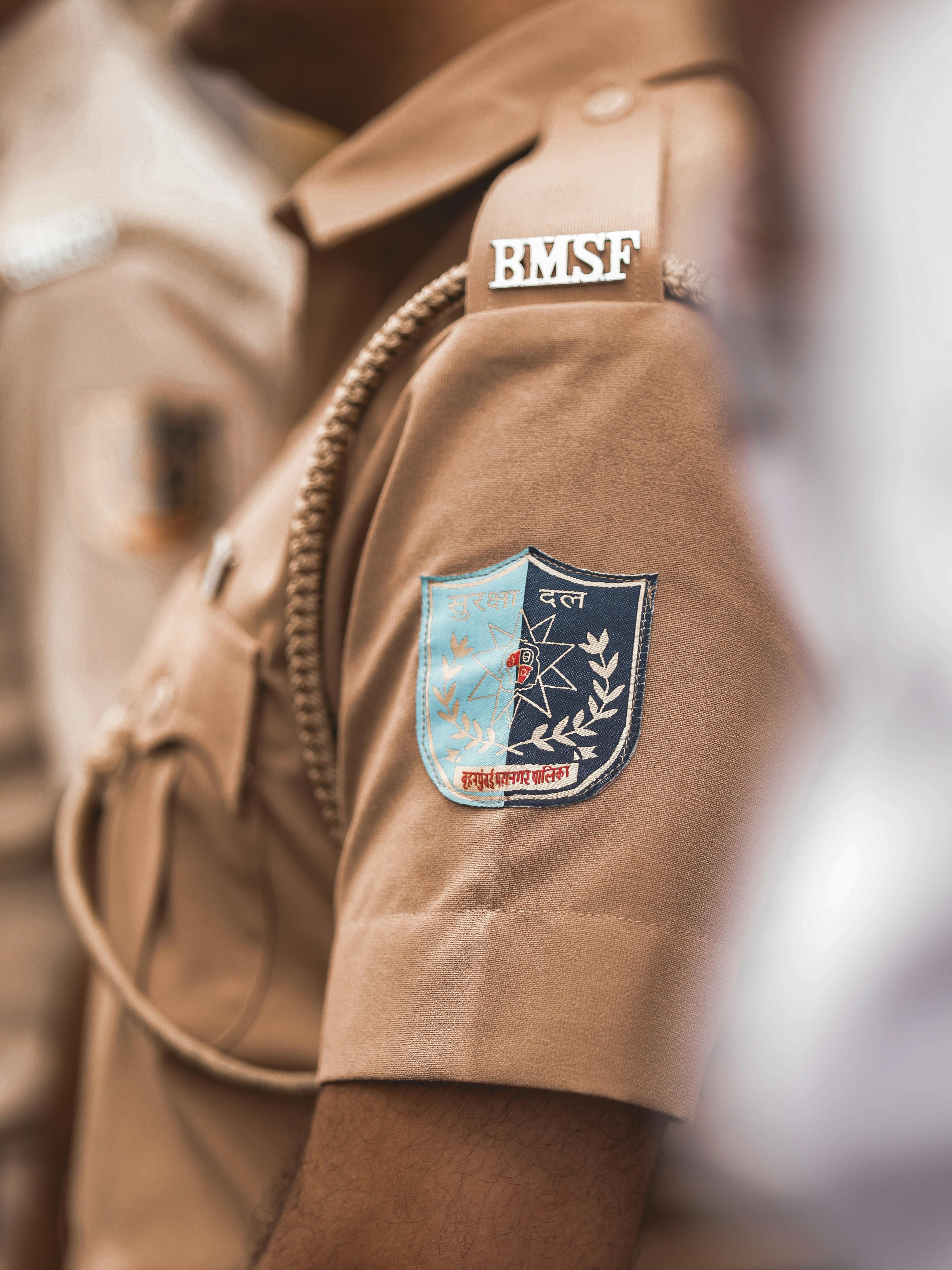 A detailed view of a brown uniform featuring a badge with text and insignia.