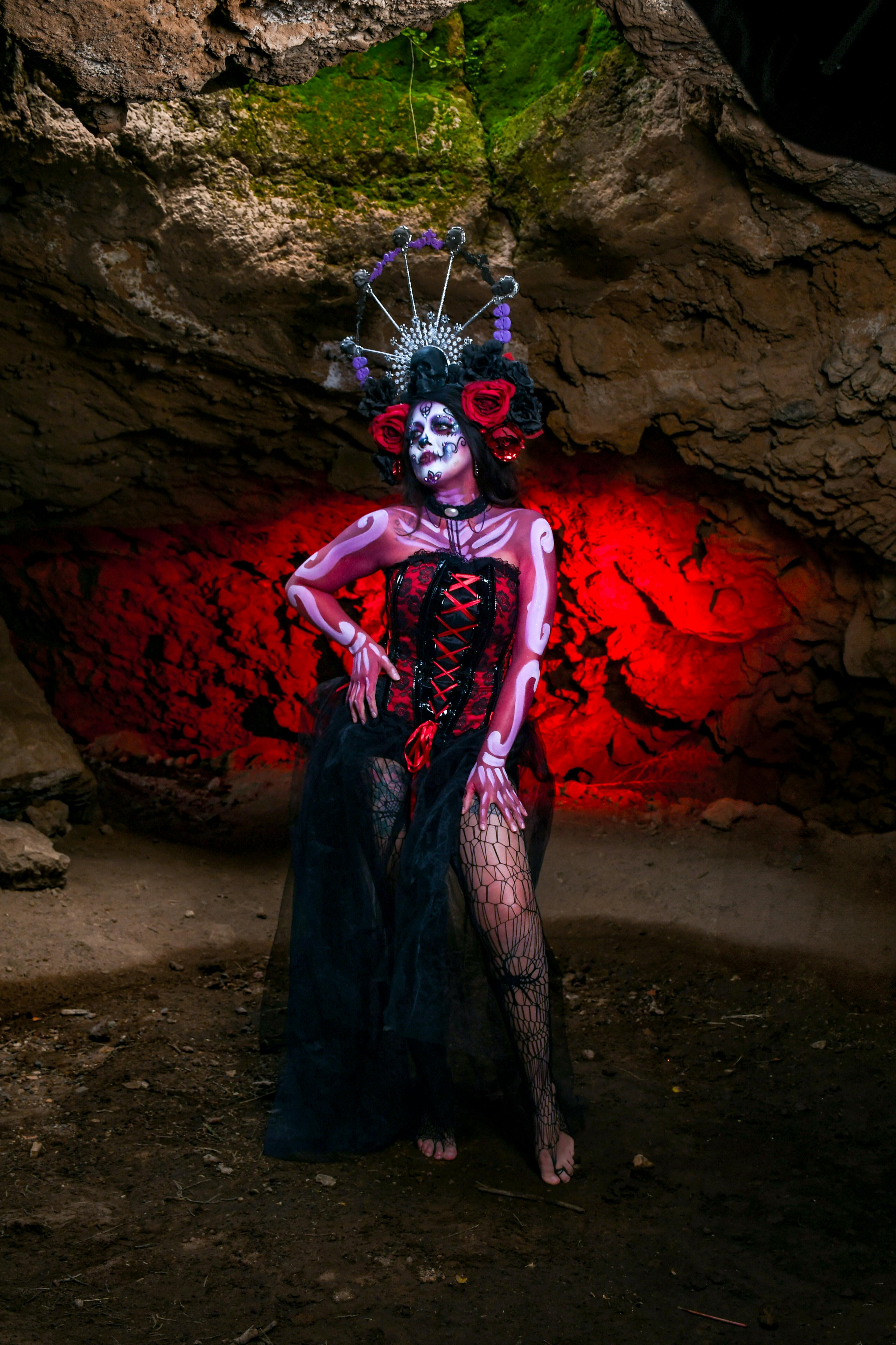 Free Gothic figure in elaborate costume with red lighting in a cave emphasizing a Halloween theme. Stock Photo