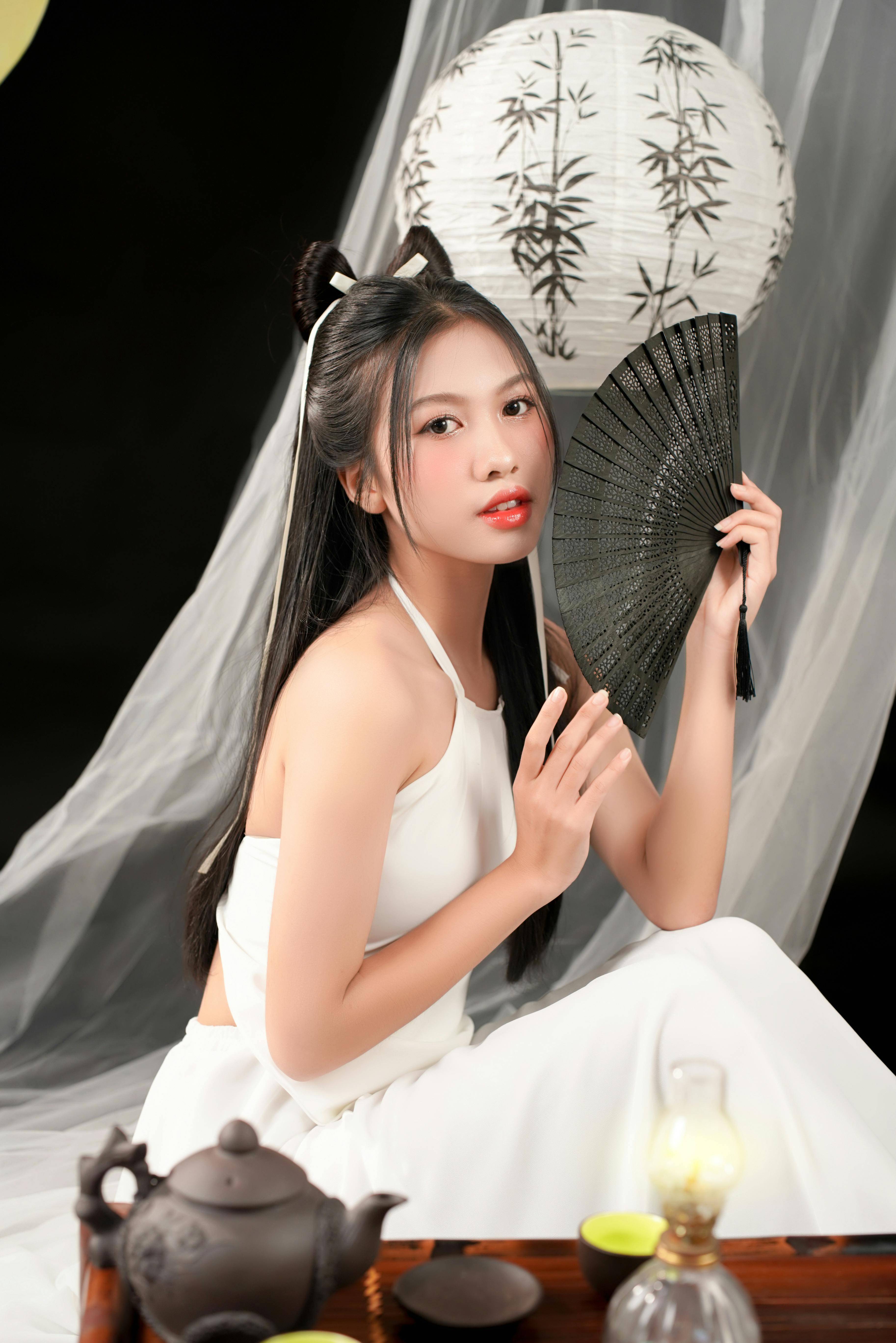 身着传统服饰的亚洲女性手持扇子，展现优雅与文化之美