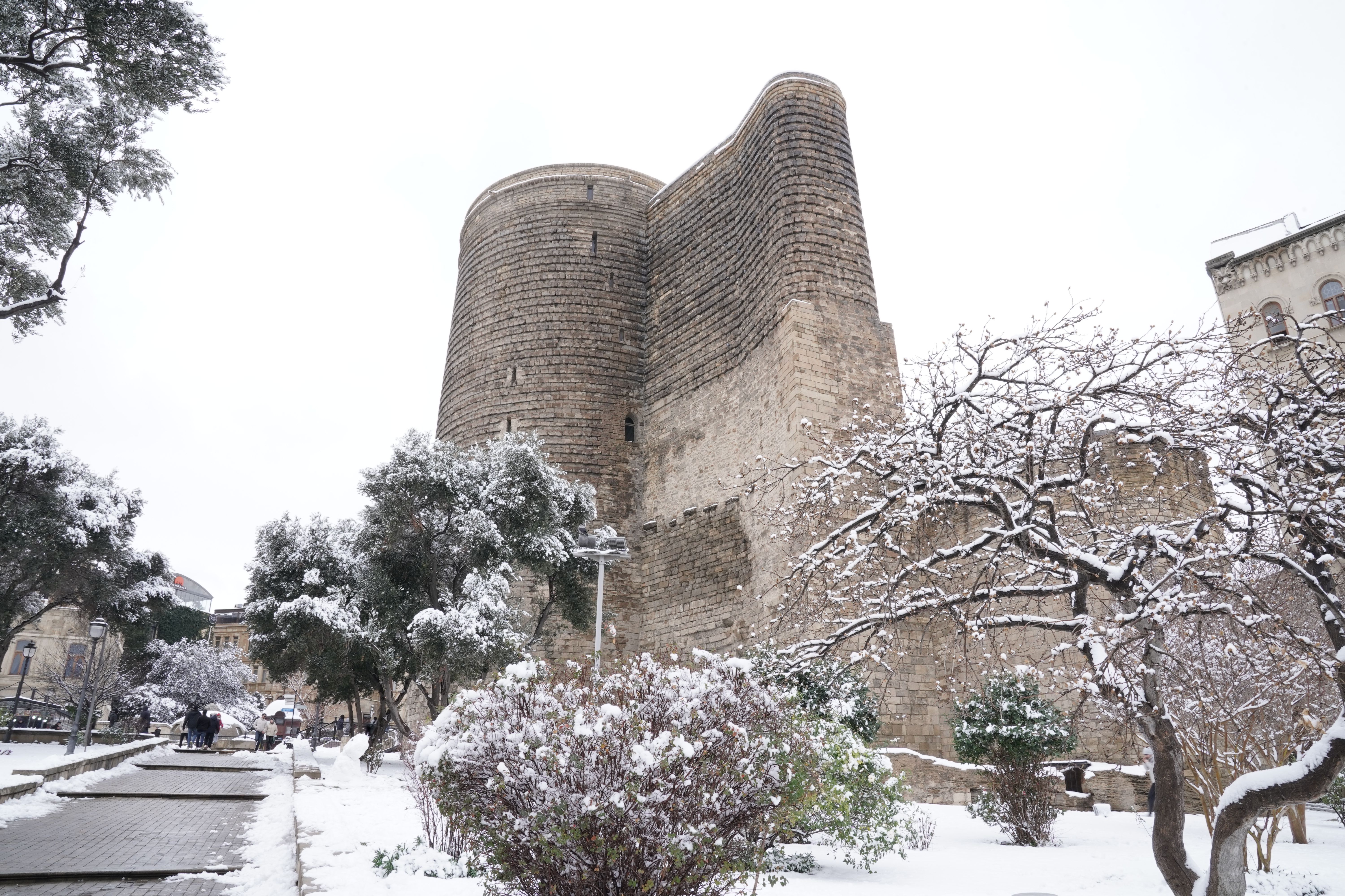 Snow-covered Maiden Tower surrounded by winter landscape in Baku, Azerbaijan.