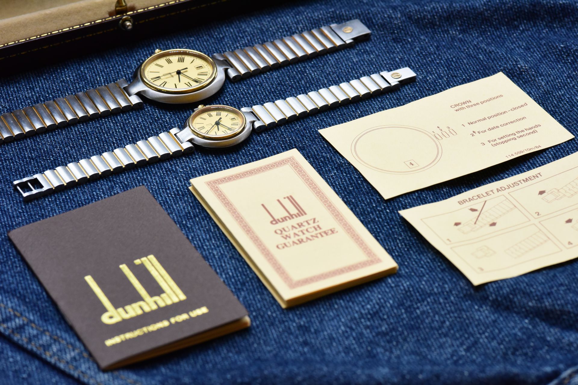 Two vintage Dunhill watches with manuals on denim surface, showcasing classic luxury style.