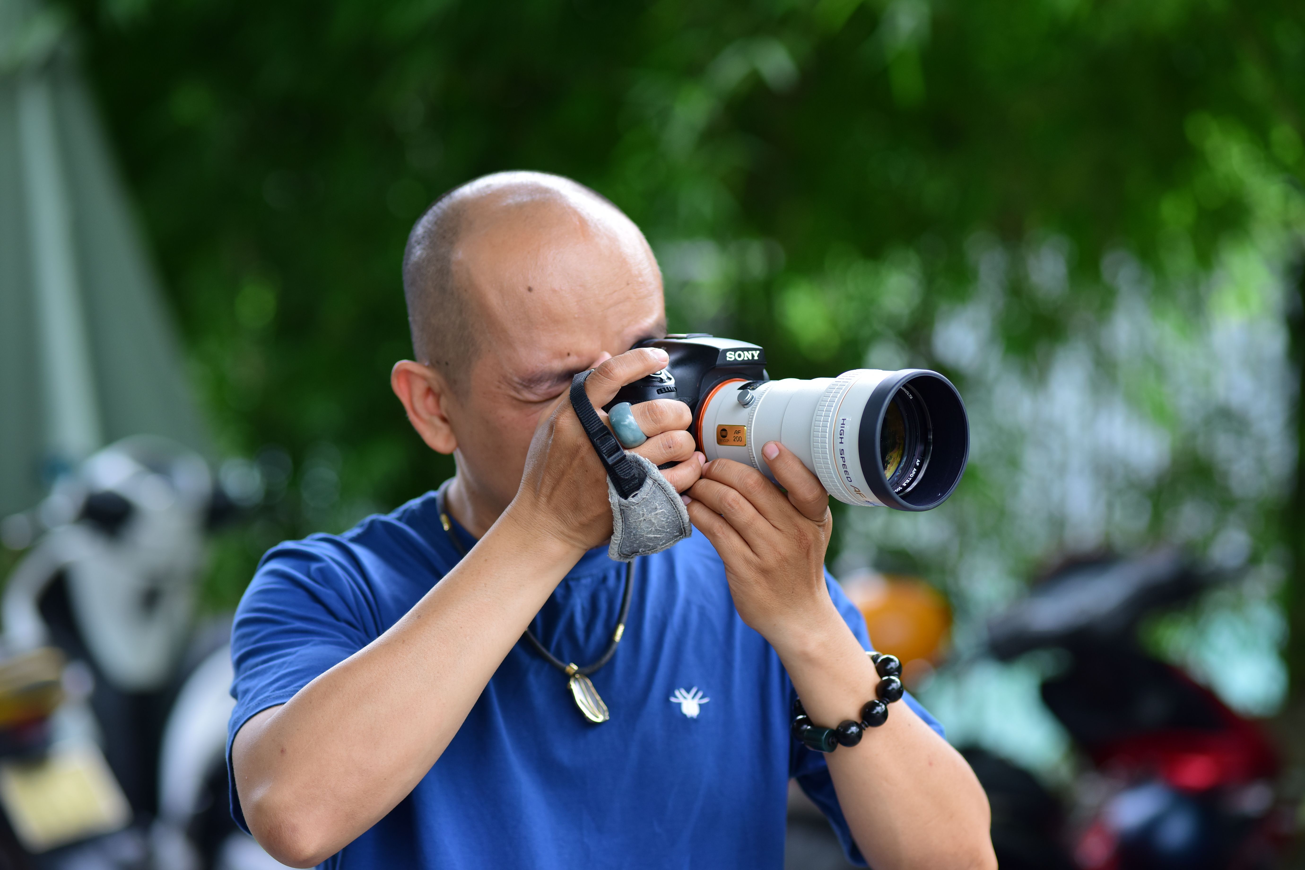 Photographer focusing with camera outdoors, capturing moments with precision.