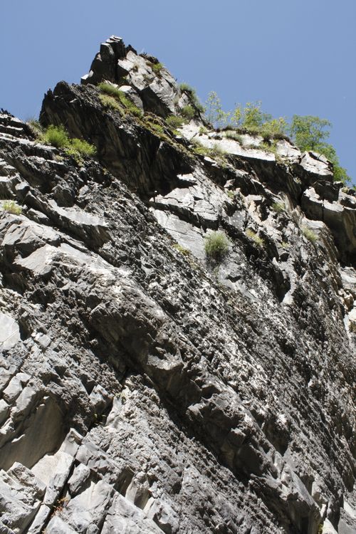 Free A striking image of a rugged cliff face against a clear blue summer sky, highlighting natural textures. Stock Photo