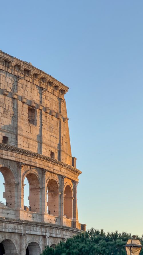 Free A serene view of the Colosseum in Rome, Italy, captured during sunset with a clear sky. Stock Photo