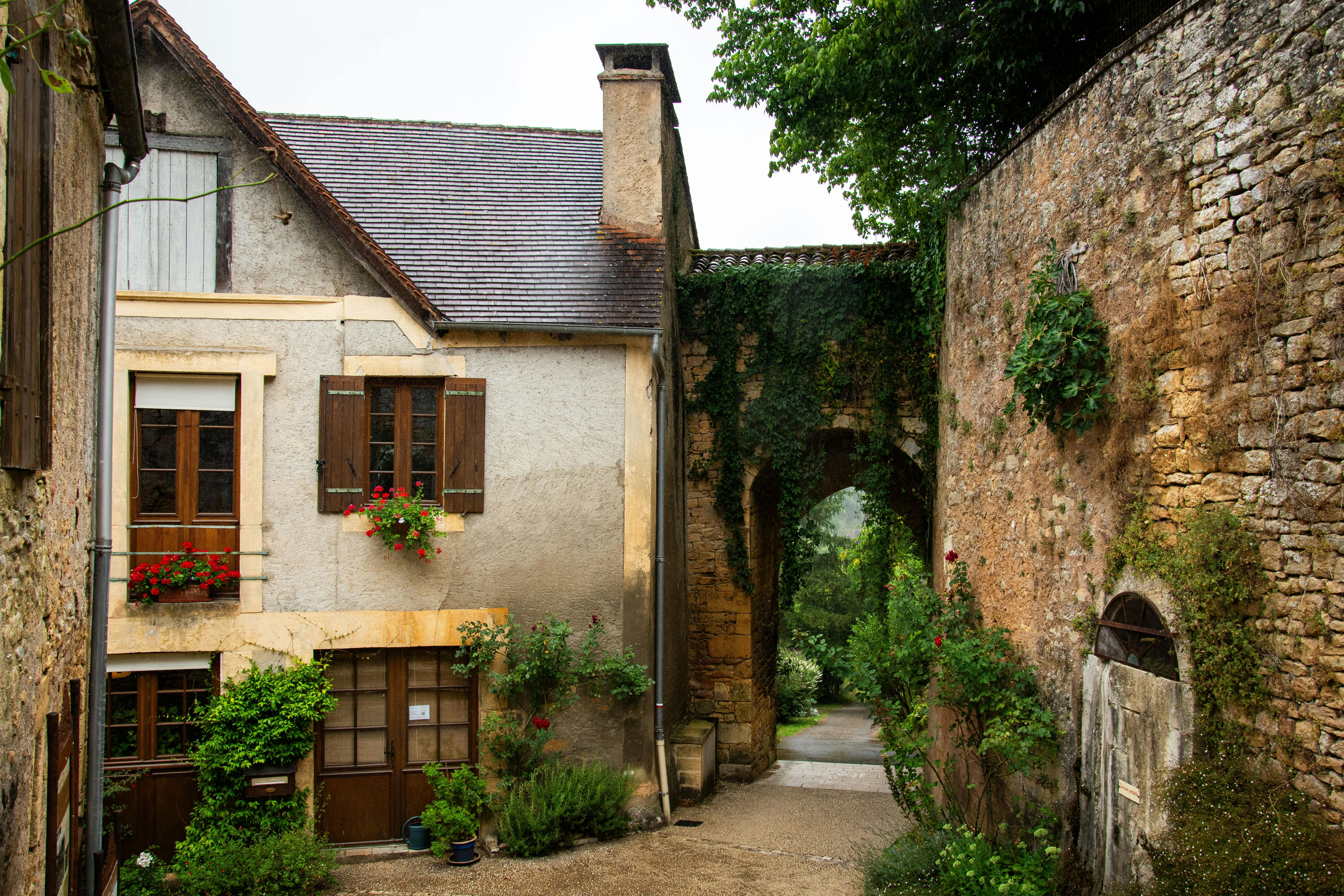 Scène de village pittoresque en Nouvelle-Aquitaine, France, avec de charmantes maisons en pierre et une verdure luxuriante.