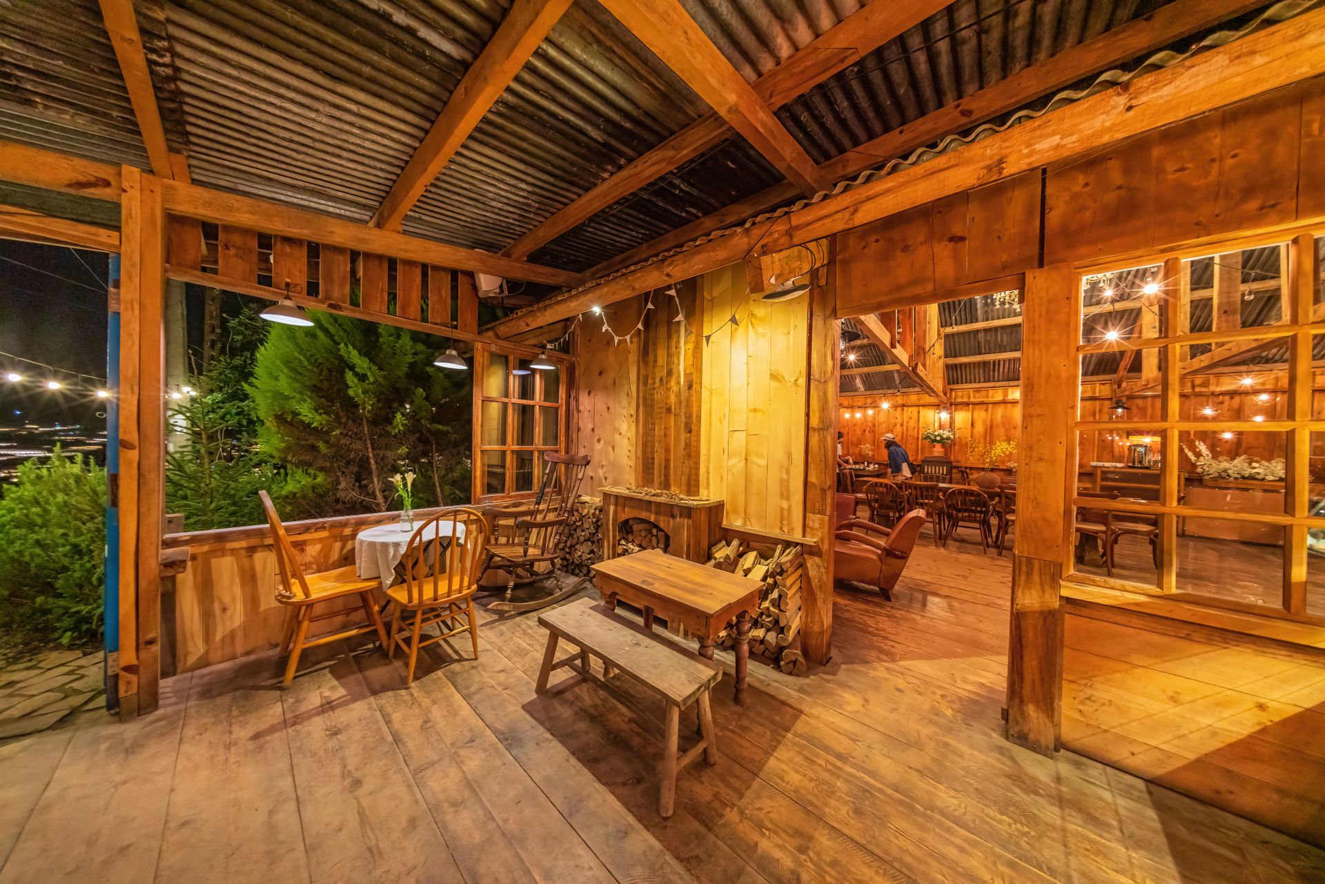 Warm, inviting rustic wooden lodge interior with glowing string lights and wooden furniture at night.