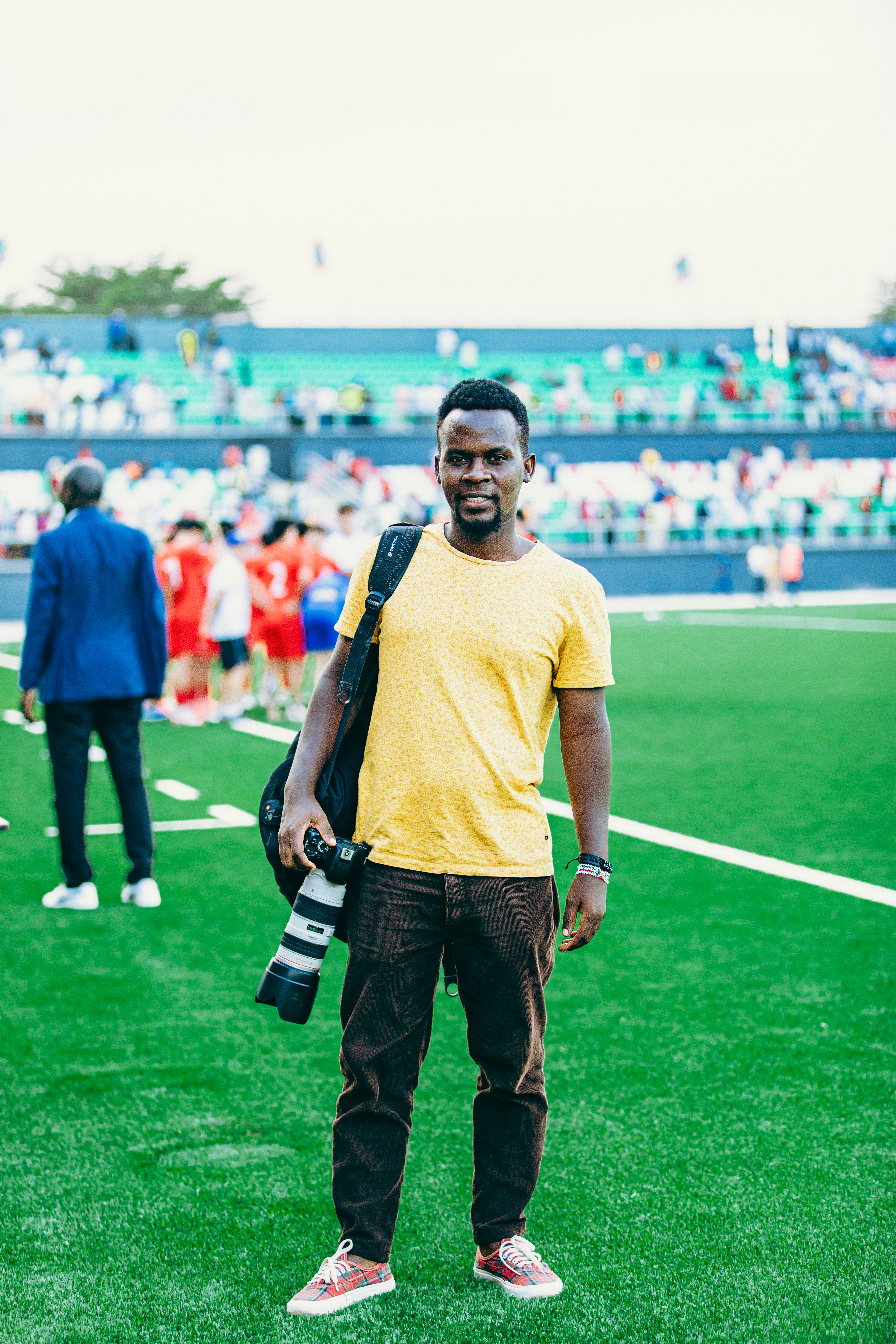Photographer standing on a soccer field with camera gear, capturing a sports event.
