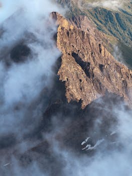 Stunning view of rugged alpine cliffs enveloped by clouds in Carinthia, Austria.