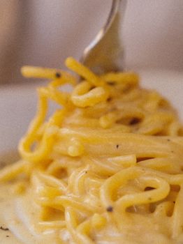 Close-up of a fork twirling creamy carbonara pasta, capturing rich texture and savory flavors.