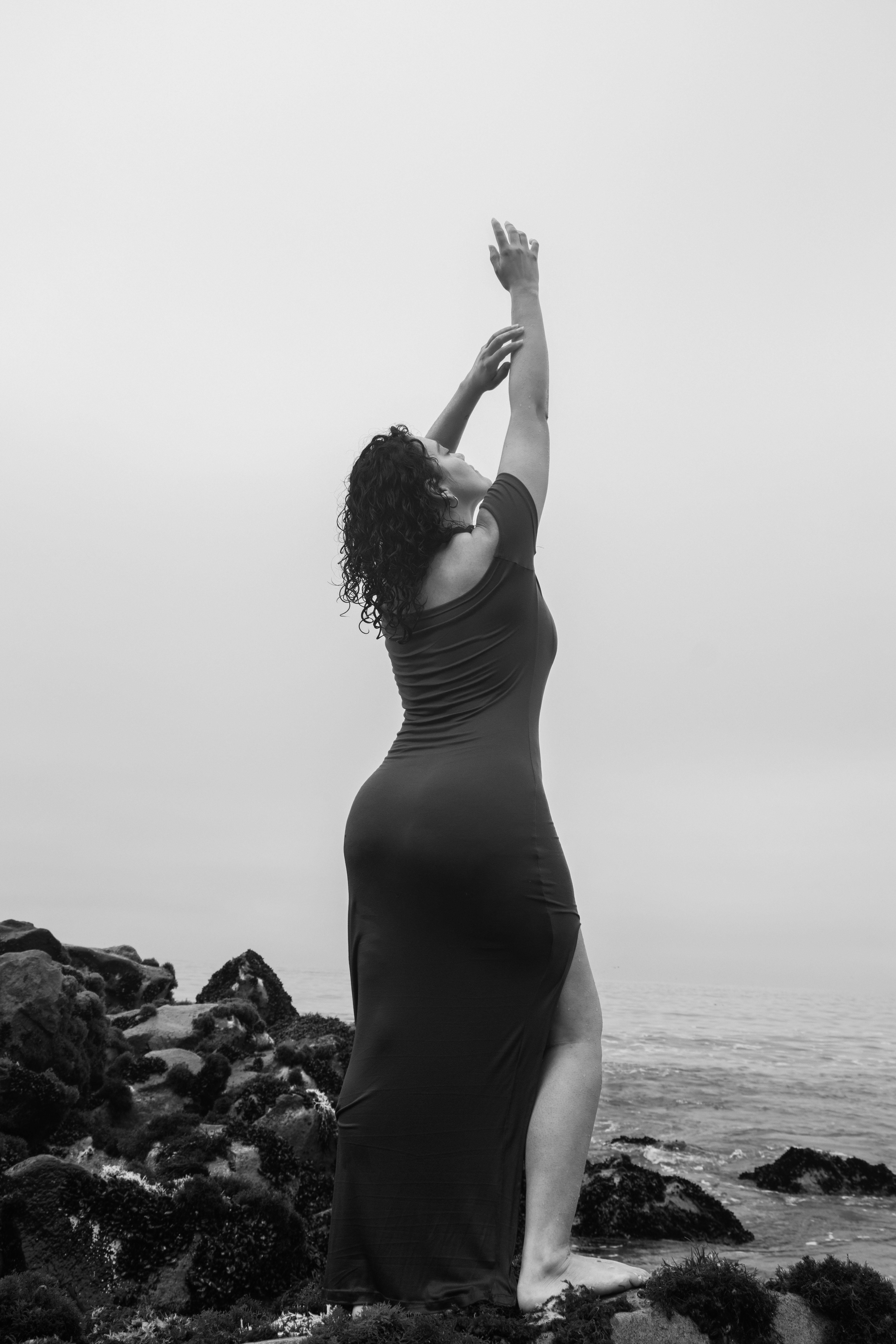 bezplatná Elegantní žena v dlouhých šatech na pláži v Limě v Peru, zachycená v černé a bílé barvě. Základová fotografie