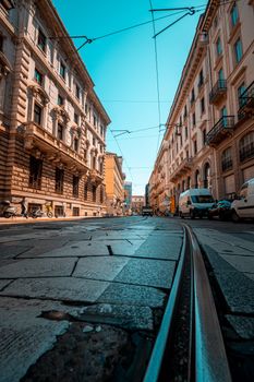 Low-angle view of a European street lined with historical buildings under a clear blue sky.