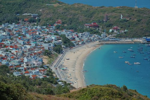Free Stunning aerial view of a beachside town surrounded by hills and vibrant blue waters. Stock Photo