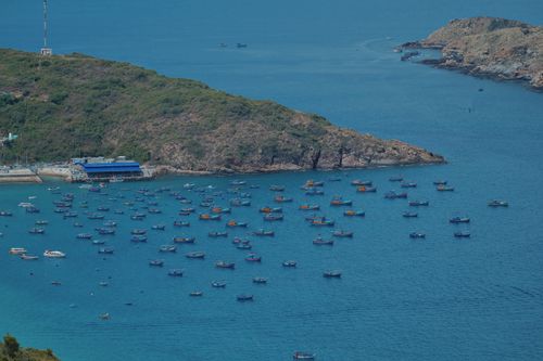Free Aerial view of vibrant boats scattered in a tranquil azure bay surrounded by rocky hills. Stock Photo