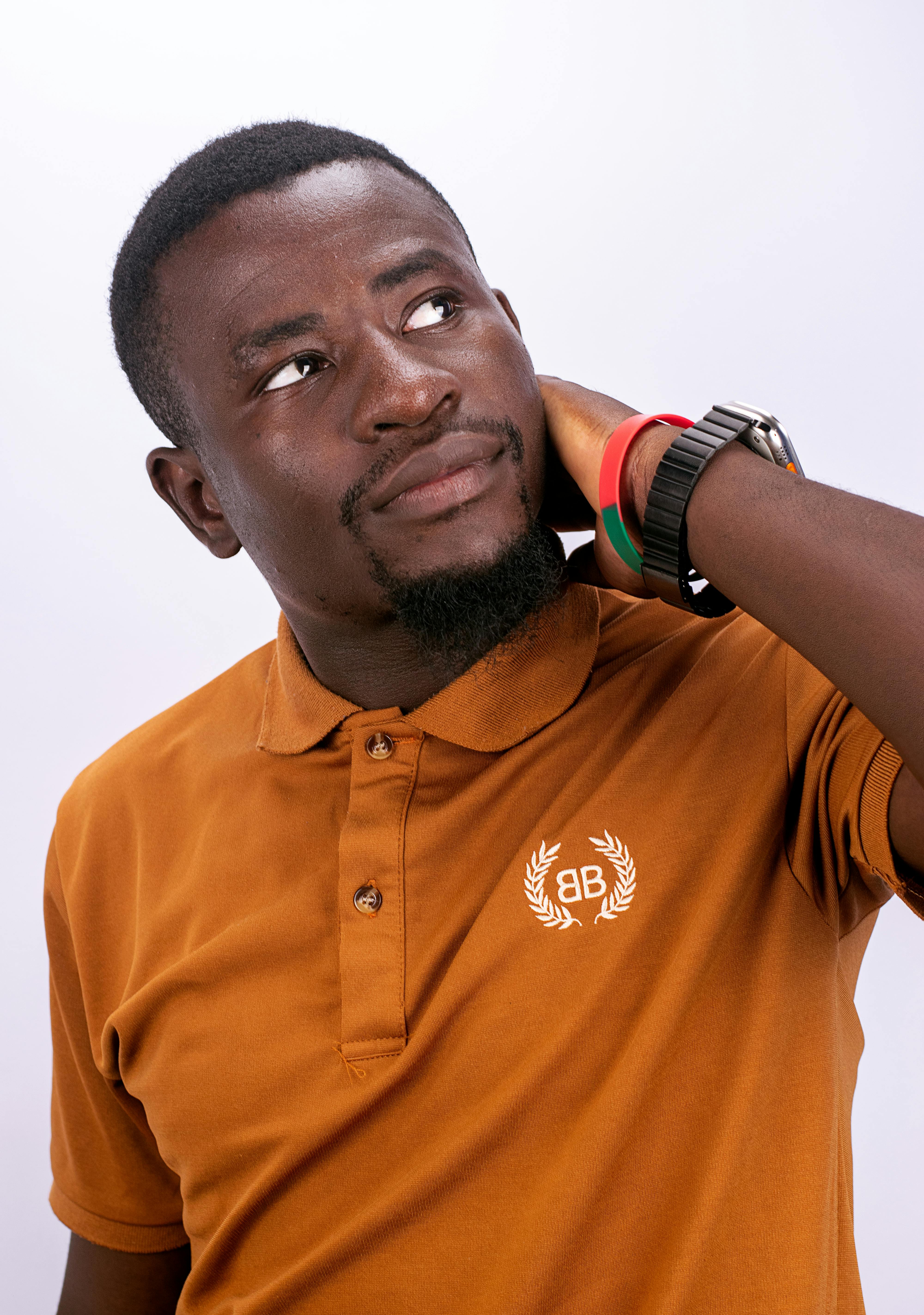 Free A thoughtful man in a brown polo shirt posing against a neutral background. Stock Photo