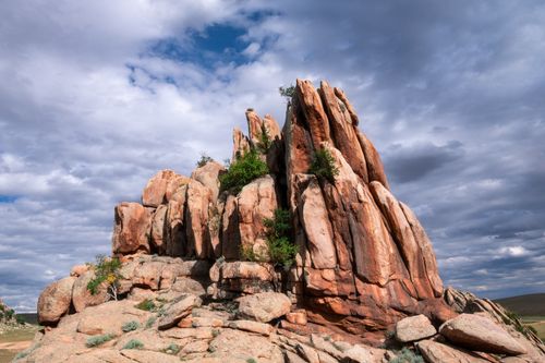 Free Scenic view of a rocky outcrop surrounded by lush greenery and a moody sky. Stock Photo